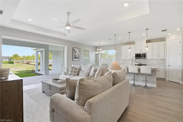 a kitchen with stainless steel appliances granite countertop a stove top oven a refrigerator a sink and white cabinets with wooden floor