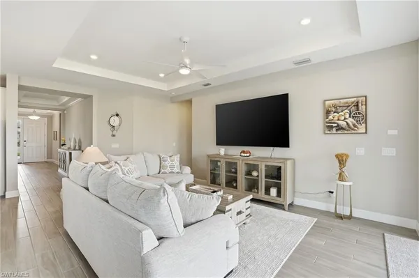 a living room with furniture kitchen view and a wooden floor
