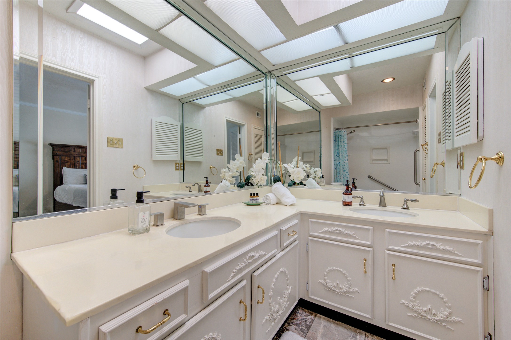 2232 South Piney Point Road, Unit 110 Houston, TX 77063 - Photo 12 of 21 Elegant primary bathroom featuring double vanities, expansive mirrors, abundant natural-style lighting, and an updated shower—creating a bright and luxurious spa-like retreat.
