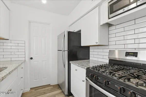 an empty room with wooden floor chandelier fan and windows
