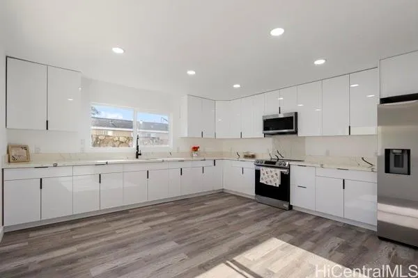 a large kitchen with granite countertop a stove top oven a sink a counter space and cabinets