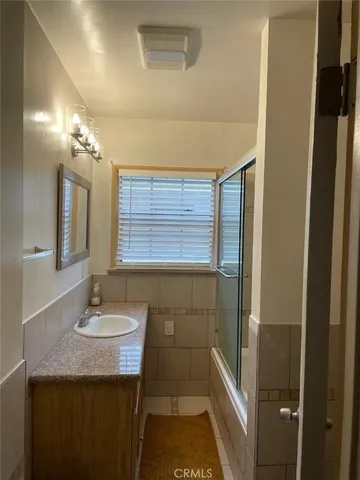 a bathroom with a granite countertop sink a large mirror and a shower