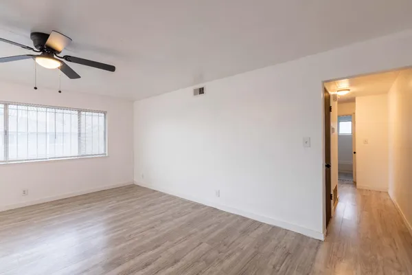 a view of empty room with wooden floor and fan