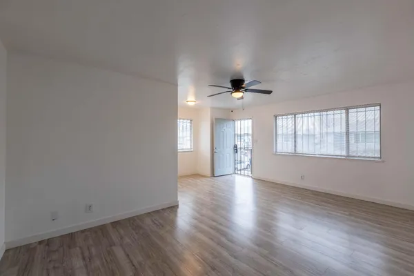 a view of an empty room with a window and wooden floor