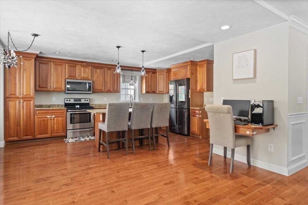 57 Partridge Hill Road Sutton, MA 01590 - Photo 11 of 40 a open kitchen with stainless steel appliances granite countertop a stove top oven a refrigerator a dining table and chairs with wooden floor