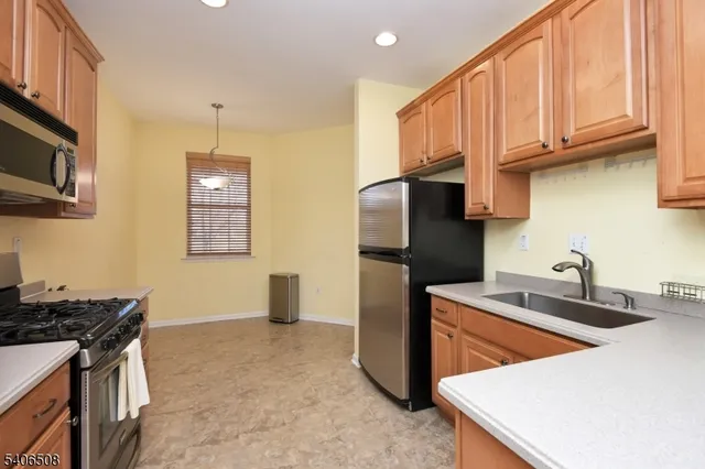 a kitchen that has a sink stainless steel appliances a refrigerator and a stove top oven