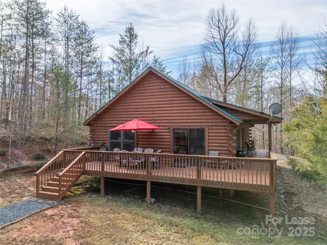 a view of house with a roof deck and wooden fence