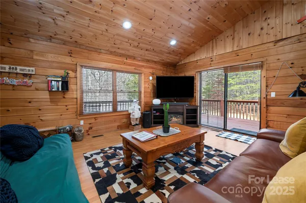 a living room with furniture a flat screen tv and a floor to ceiling window