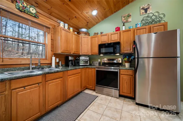 a kitchen with stainless steel appliances granite countertop a refrigerator a sink dishwasher a stove and a microwave oven