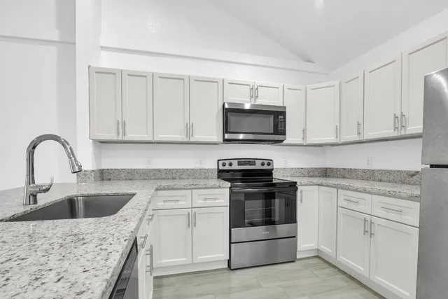 a kitchen with white cabinets stainless steel appliances and sink