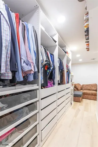 a view of walk in closet with clothes and shoes