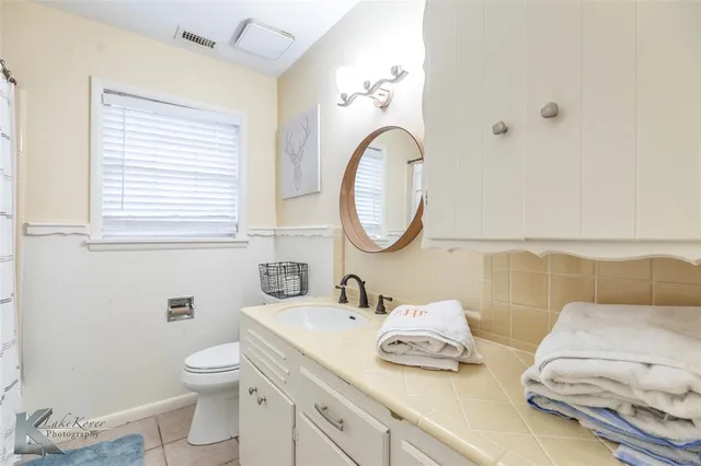 a bathroom with a granite countertop toilet a sink and a mirror