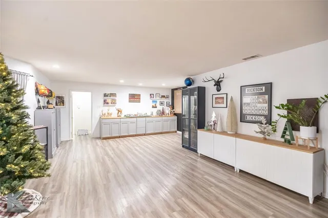 a kitchen with stainless steel appliances kitchen island granite countertop a stove top oven a sink dishwasher a dining table and chairs with wooden floor