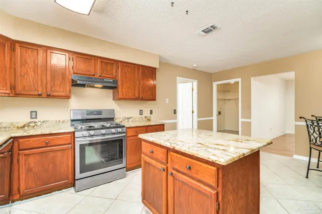 a kitchen with granite countertop kitchen island wooden cabinets and stainless steel appliances