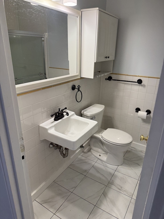 144 Kenrick Street, Unit 37 Boston, MA 02135 - Photo 4 of 12 a bathroom with a sink a toilet a mirror and shower
