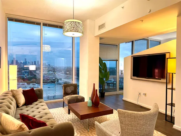 a living room with furniture a flat screen tv and a large window