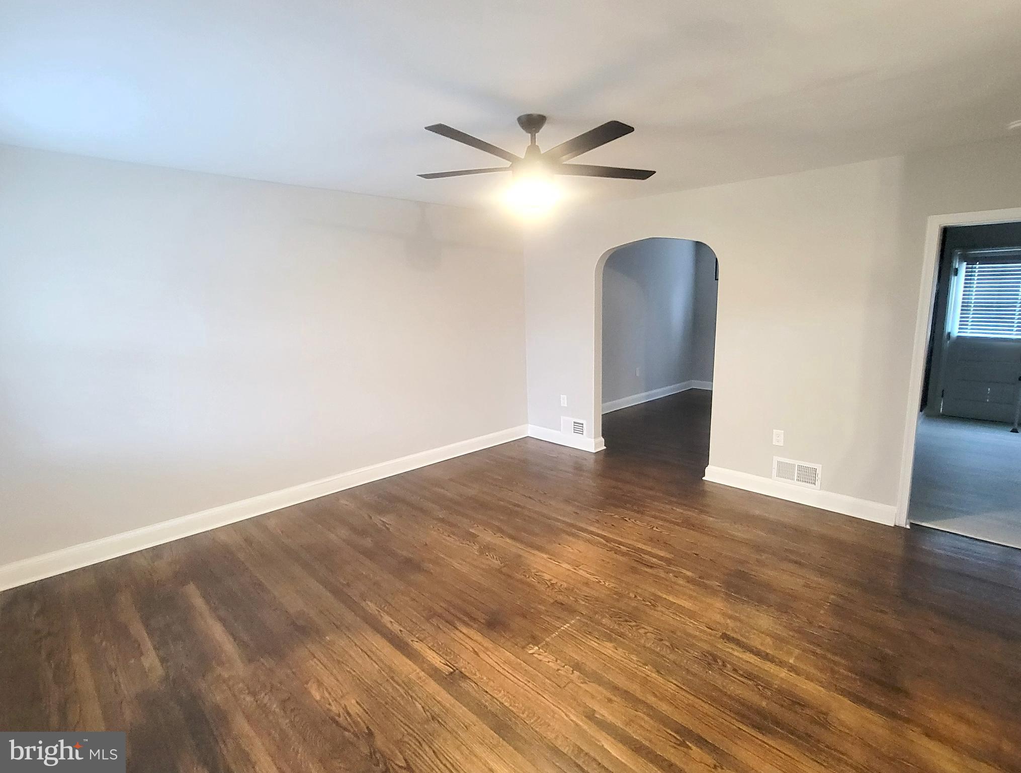 202 Edgewood Street Baltimore, MD 21229 - Photo 3 of 29 a view of an empty room with wooden floor and a ceiling fan