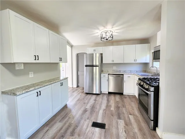 a kitchen with stainless steel appliances a white cabinets and wooden floor