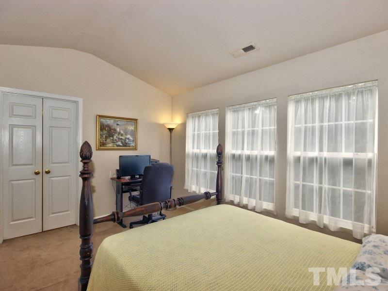 8523 Bright Loop Raleigh, NC 27613 - Photo 12 of 23 a bedroom with a bed and a desk