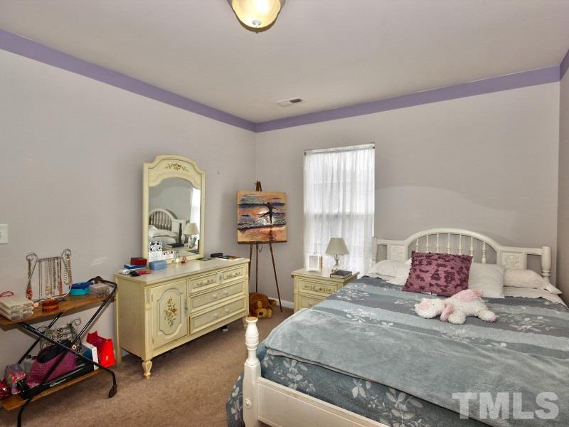 8523 Bright Loop Raleigh, NC 27613 - Photo 16 of 23 a bedroom with a bed and a chandelier