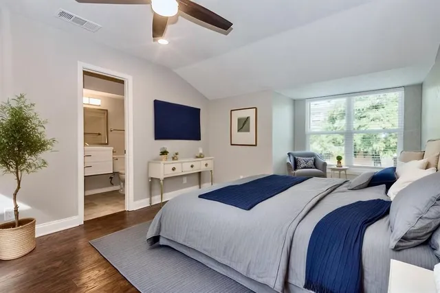 a bedroom with a bed and potted plant with wooden floor