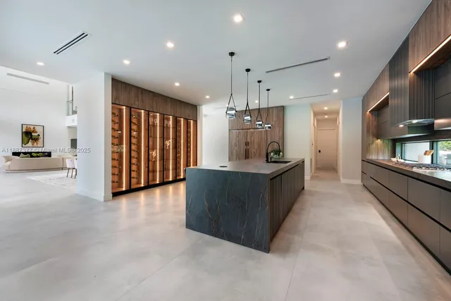 a kitchen with stainless steel appliances kitchen island granite countertop a refrigerator and a sink