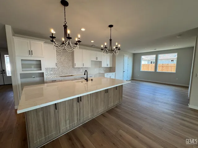 a large kitchen with kitchen island white cabinets and stainless steel appliances