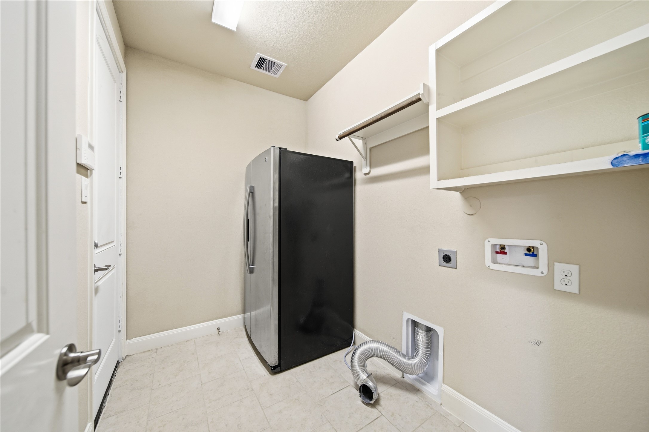 5303 Mesquite Willow Lane Rosharon, TX 77583 - Photo 23 of 32 The laundry room with tile flooring. It features open shelving, room for a second refrigerator, and hookups for a washer and dryer.