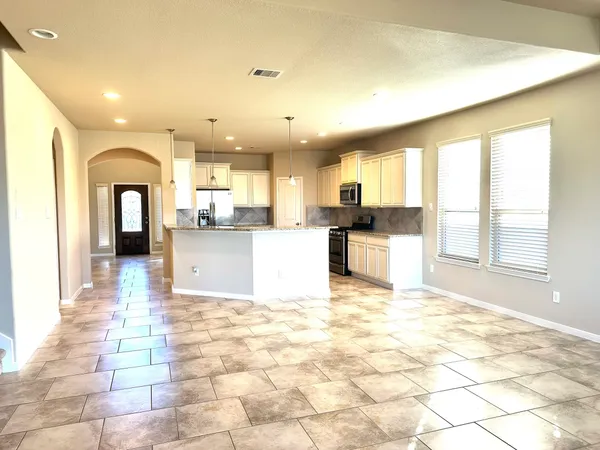 a view of a kitchen with kitchen island stainless steel appliances refrigerator sink microwave and cabinets