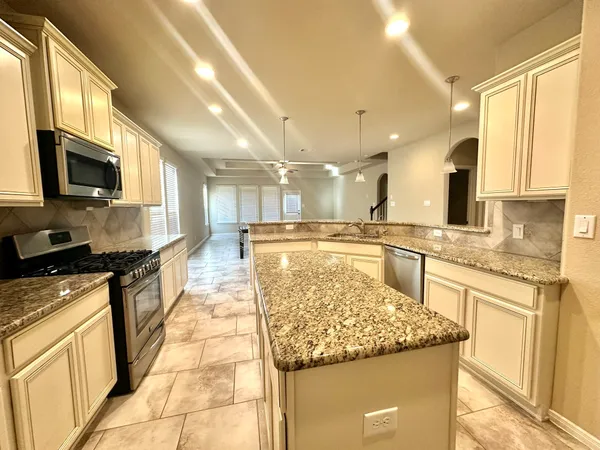 a kitchen with stainless steel appliances granite countertop a stove top oven a sink dishwasher and a microwave oven with white cabinets