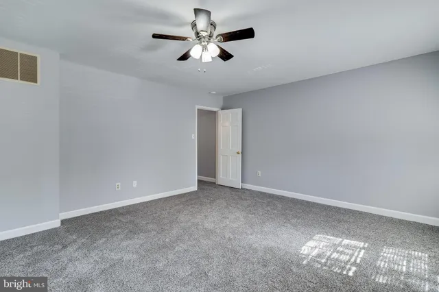 an empty room with a chandelier fan and windows