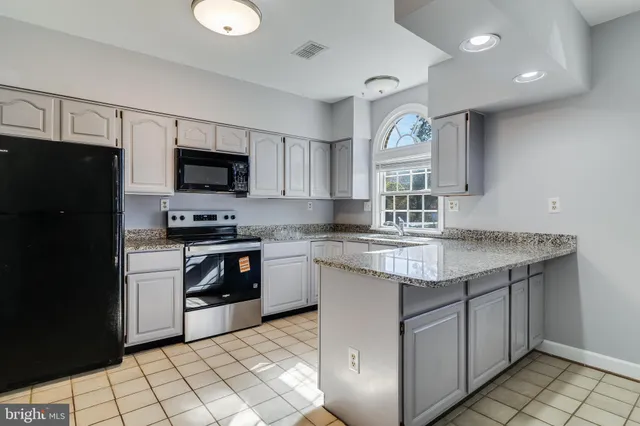a kitchen with granite countertop a stove top oven microwave and cabinets