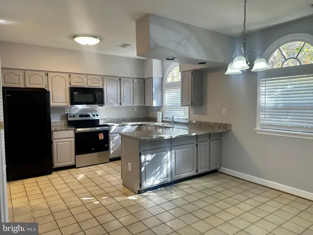 a kitchen with stainless steel appliances granite countertop a refrigerator a sink a stove a microwave and island