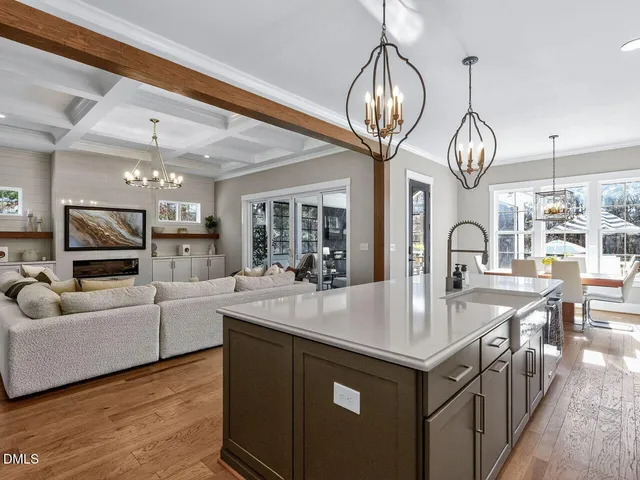a large kitchen with kitchen island a stove a sink a oven and a chandelier