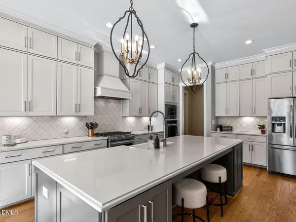 a dining room with wooden floor a chandelier a glass table and chairs