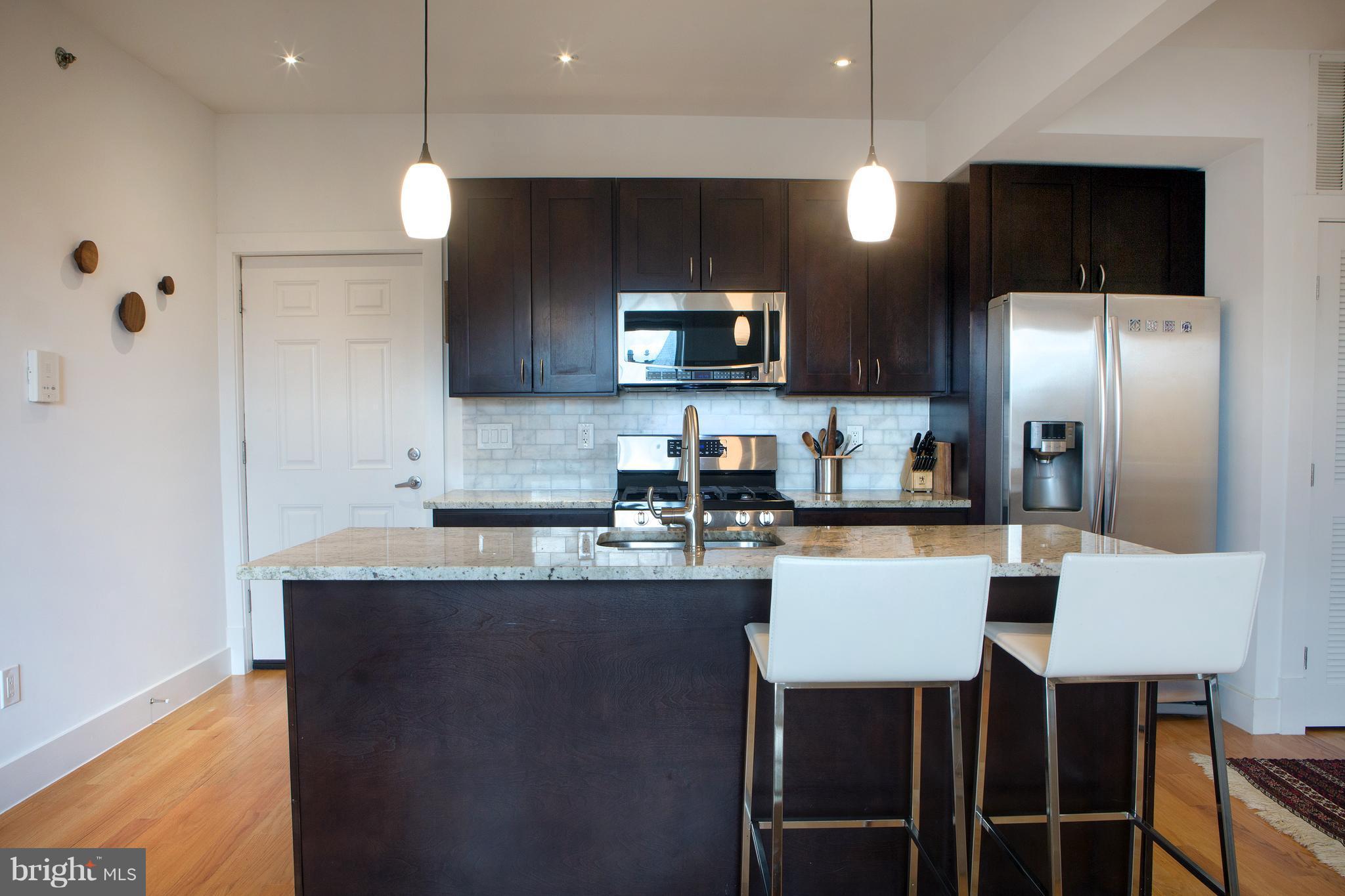 1700 2nd Street Northwest, Unit 9 Washington, DC 20001 - Photo 5 of 26 a kitchen with stainless steel appliances granite countertop a refrigerator a sink a stove a microwave and white cabinets with wooden floor