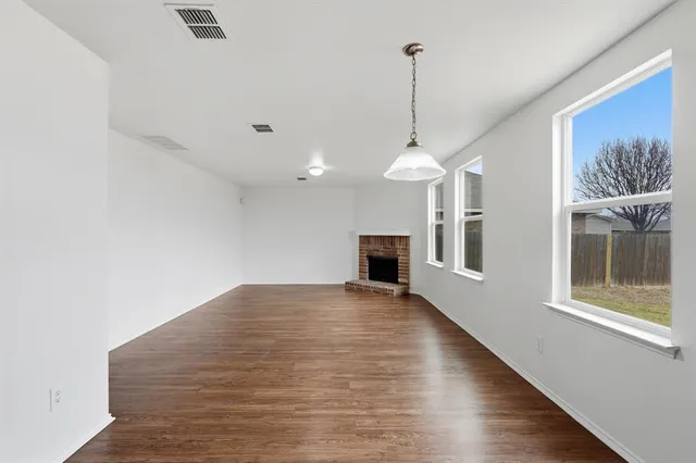 a view of an empty room with window and kitchen view