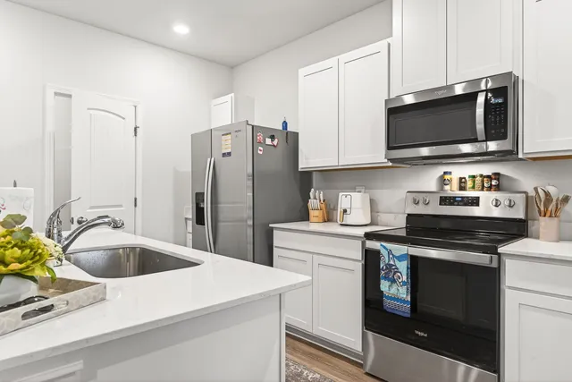 a kitchen with stainless steel appliances granite countertop a sink a stove a microwave and refrigerator