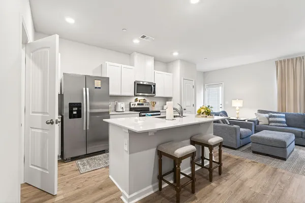 a kitchen with a refrigerator a stove a sink dishwasher with a dining table and chairs