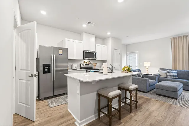 a kitchen with a refrigerator a stove a sink dishwasher with a dining table and chairs