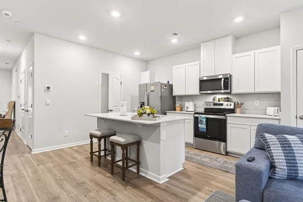 a kitchen with a sink a microwave a refrigerator and chairs