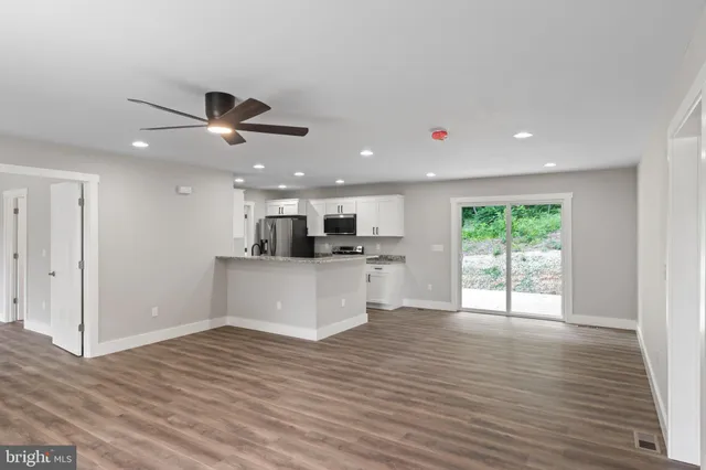 a kitchen with stainless steel appliances granite countertop a sink stove refrigerator and cabinets with wooden floor