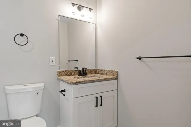 a bathroom with a granite countertop bathtub shower sink vanity and toilet