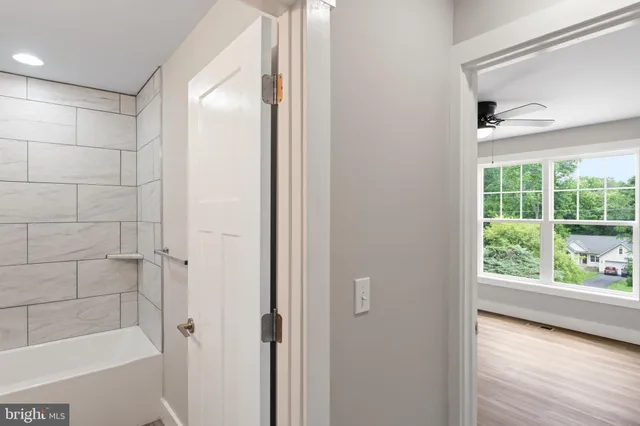 an empty room with wooden floor fan and windows