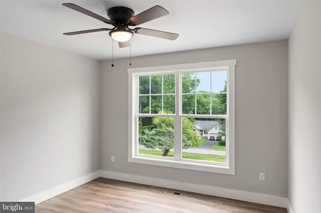 an empty room with wooden floor and ceiling fan