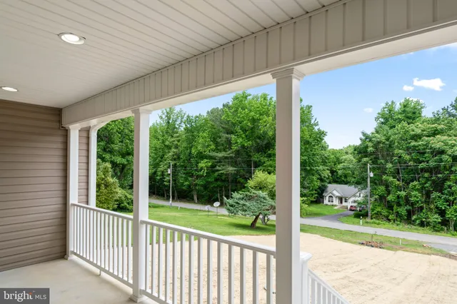an empty room with wooden floor chandelier fan and windows