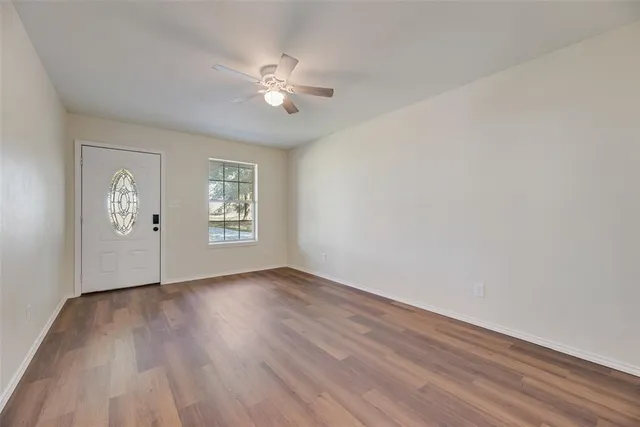 a view of an empty room with wooden floor and a window