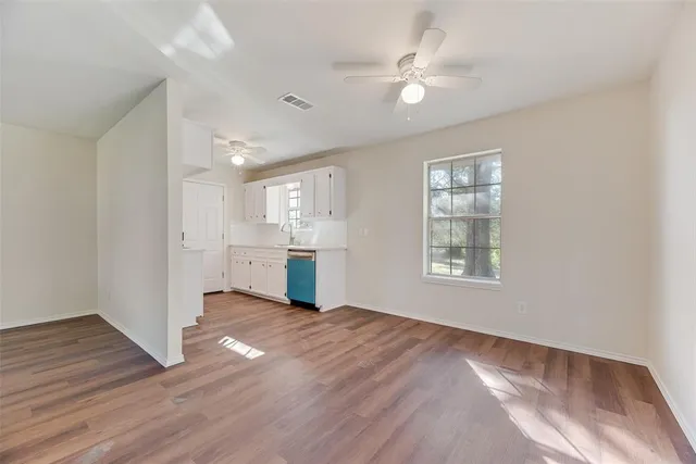 a view of an empty room with window and wooden floor