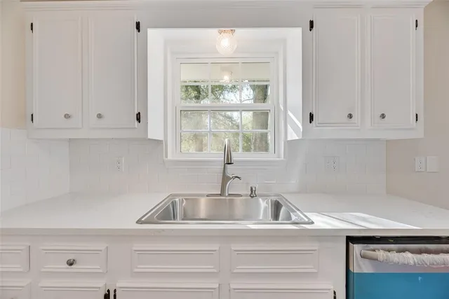 a kitchen with granite countertop white cabinets and a sink