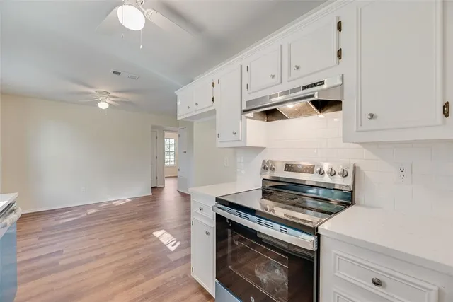 a kitchen with granite countertop a stove and white cabinets